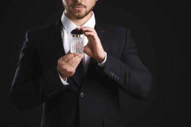 Esmer arka planda parfüm şişesi olan yakışıklı bir genç.