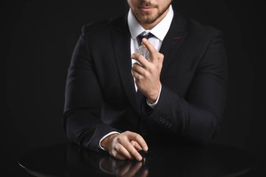 Esmer arka planda parfüm şişesi olan yakışıklı bir genç.