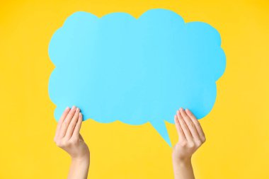 Female hands with blank speech bubble on color background