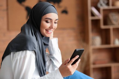 Evinde cep telefonu olan güzel bir Arap kadın.