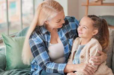 Küçük kız ve büyükanne evde birlikte vakit geçiriyorlar.