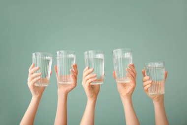 Renkli arka planda su bardakları olan kadın elleri