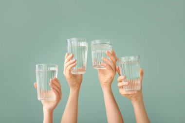 Renkli arka planda su bardakları olan kadın elleri