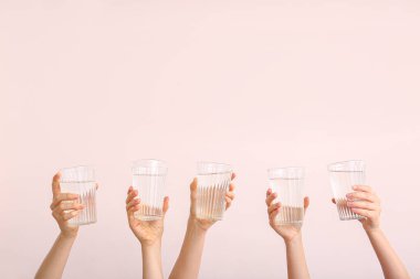 Renkli arka planda su bardakları olan kadın elleri