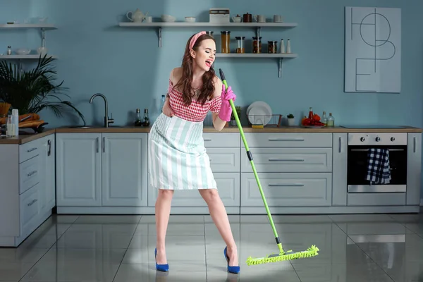 Beautiful young housewife singing while cleaning kitchen — Stock Photo, Image