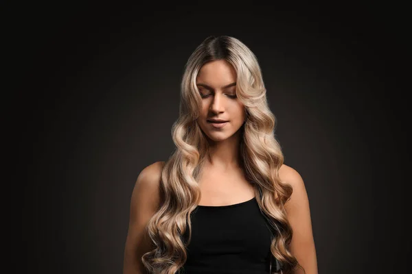 Belle jeune femme aux cheveux bouclés sur fond sombre — Photo