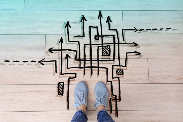 Person standing on floor near arrows pointing in different directions, top view. Concept of choice — Stock Photo, Image