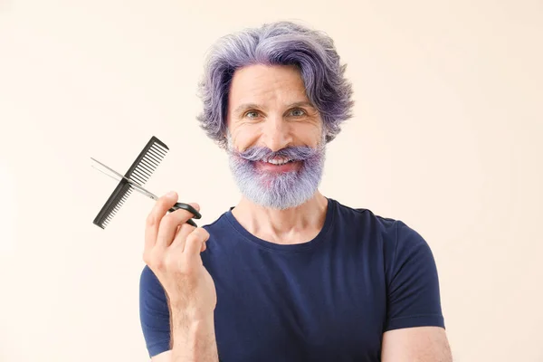 明るい背景に染め髪とひげを持つ成熟した男性理容師 — ストック写真