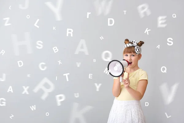 小女孩，带着扩音器和许多轻背景的字母。 外语的学习 — 图库照片