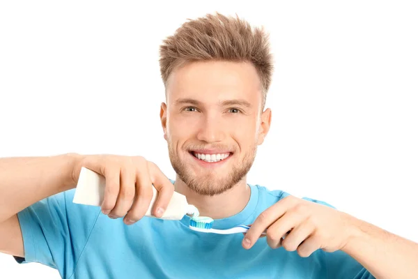 Fiatal férfi fogkefével és paszta fehér háttér — Stock Fotó