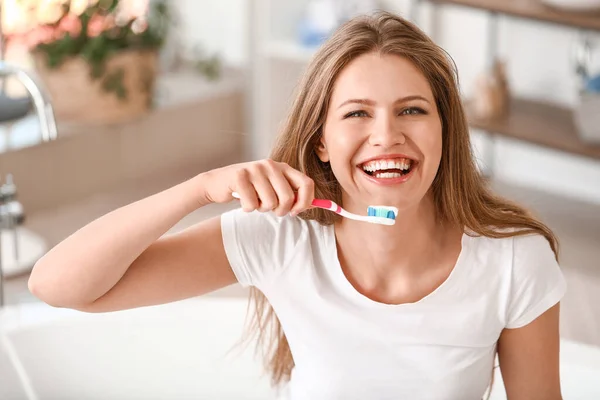 Mladá žena čistí zuby doma — Stock fotografie