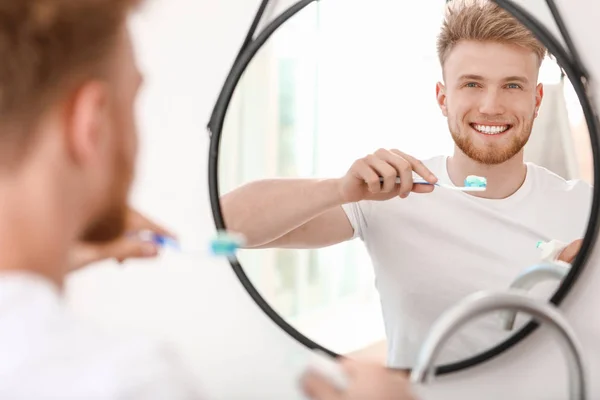 Hombre joven cepillándose los dientes en casa — Foto de Stock