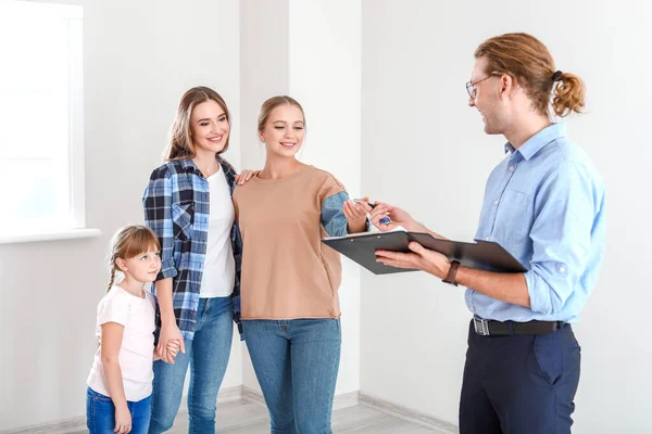 Real estate agent giving a key from new house to lesbian family — 스톡 사진