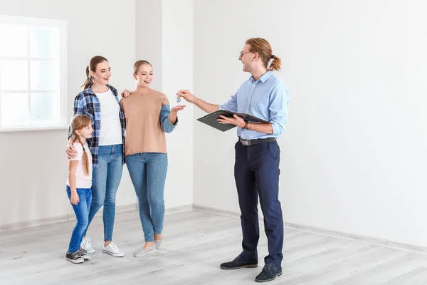 Agente imobiliário dando uma chave de casa nova para família lésbica — Fotografia de Stock