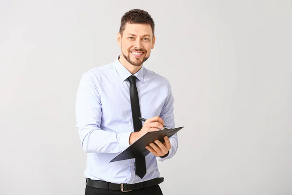 Bonito homem de negócios com área de transferência no fundo branco — Fotografia de Stock