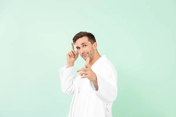 Handsome man in bathrobe pointing at viewer on color background — Stock Photo, Image
