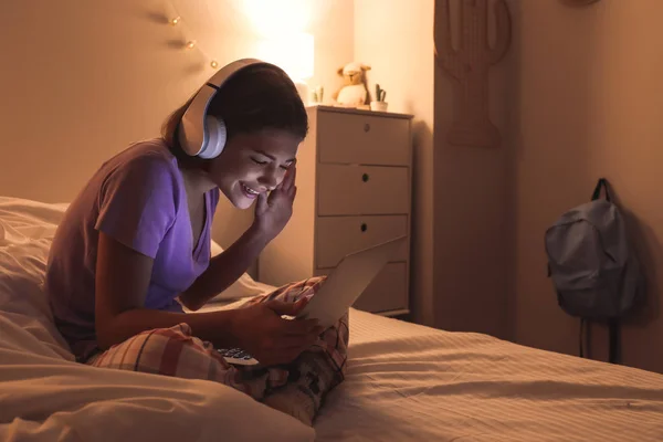 Adolescente con portátil escuchando música en el dormitorio por la noche —  Fotos de Stock