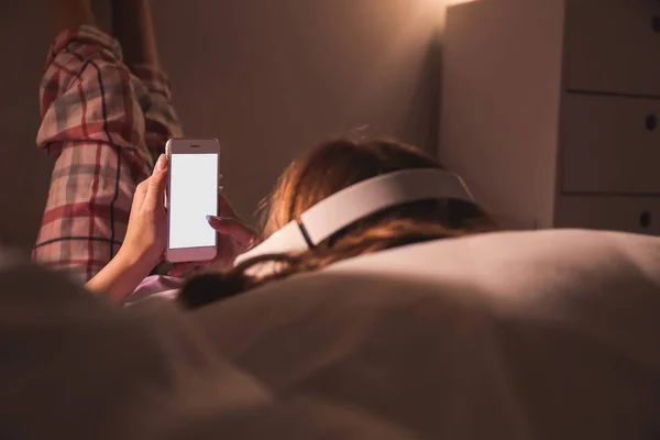 Teenage dívka s mobilním telefonem poslech hudby při ležení v posteli v noci — Stock fotografie