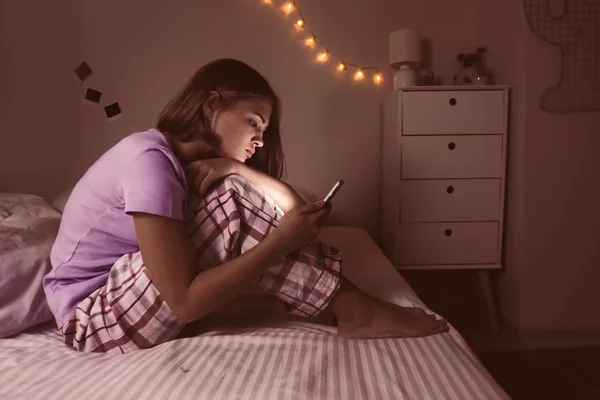 Dospívající dívka s mobilním telefonem v ložnici v noci — Stock fotografie
