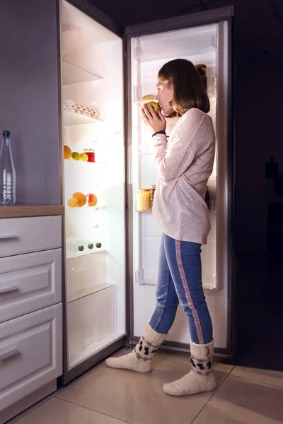 Teenage girl near open refrigerator at night