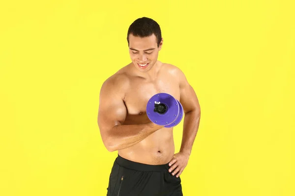 Sporty African-American man with dumbbell on color background — Stock Photo, Image