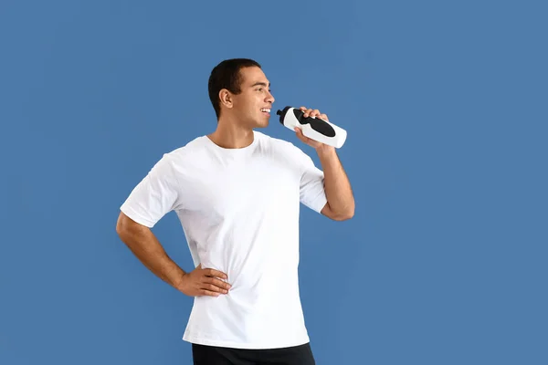 Deportivo hombre afroamericano con botella de agua sobre fondo de color — Foto de Stock