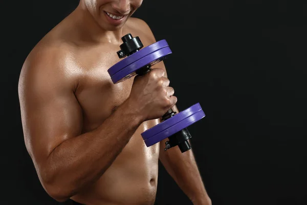 Sporty African-American man with dumbbell on dark background — Stock Photo, Image