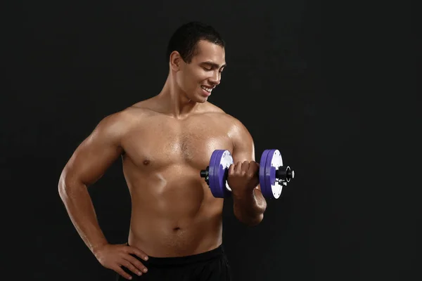 Sporty African-American man with dumbbell on dark background — Stock Photo, Image