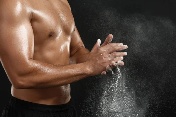 Sporty African-American man applying talc powder on hands against dark background, closeup — Stock Photo, Image