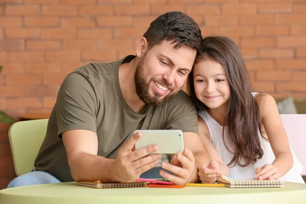Far och dotter med mobiltelefon hemma — Stockfoto