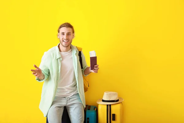 Junger männlicher Tourist mit Gepäck auf farbigem Hintergrund — Stockfoto