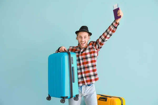 Happy male tourist with luggage on color background — Stock Photo, Image