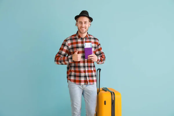 Young male tourist with luggage on color background — Stock Photo, Image