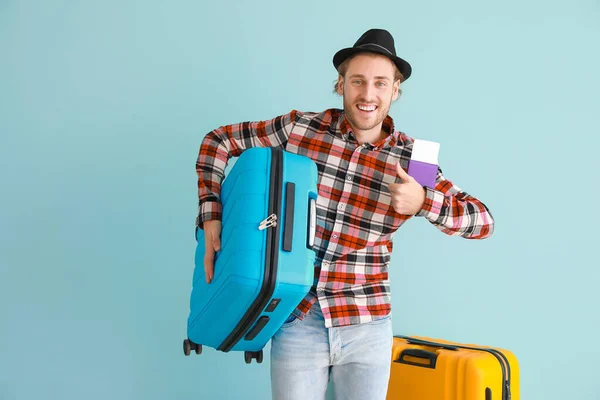 Young male tourist with luggage on color background — Stock Photo, Image