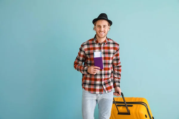 Junger männlicher Tourist mit Gepäck auf farbigem Hintergrund — Stockfoto