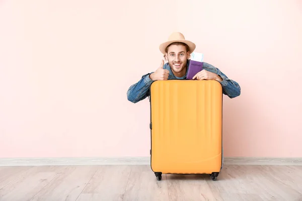 Joven turista masculino con equipaje cerca de la pared de color — Foto de Stock