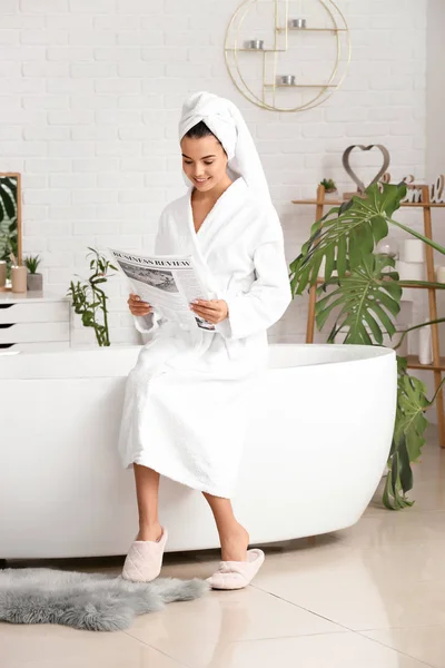Gyönyörű fiatal nő olvas újságot a fürdőszobában — Stock Fotó