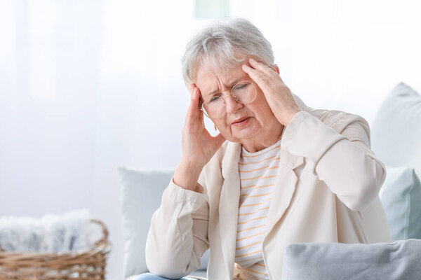 Старшая женщина страдает головной болью дома
