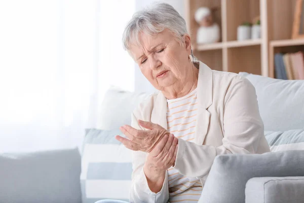 Senior woman suffering from pain in wrist at home — Stock Photo, Image
