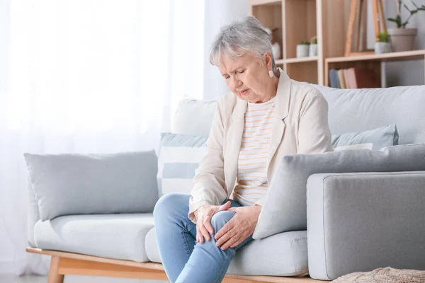 Mujer mayor que sufre de dolor en la rodilla en casa — Foto de Stock