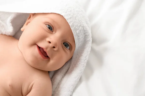 Portrait of cute little baby with towel lying on bed — ストック写真