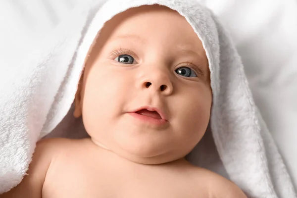 Portret van schattige baby met handdoek liggend op bed — Stockfoto