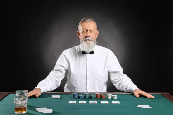 Mature male banker at table in casino — Stock Photo, Image