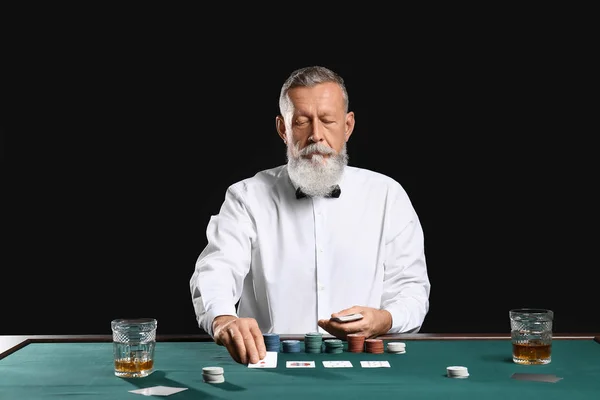 Mature male banker at table in casino — Stock Photo, Image