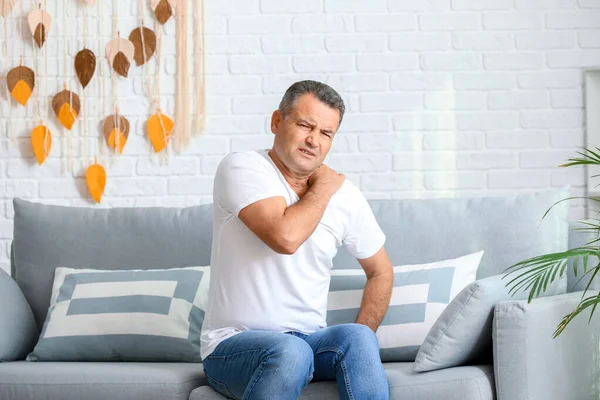 Mature man suffering from pain in shoulder at home — Stock Photo, Image