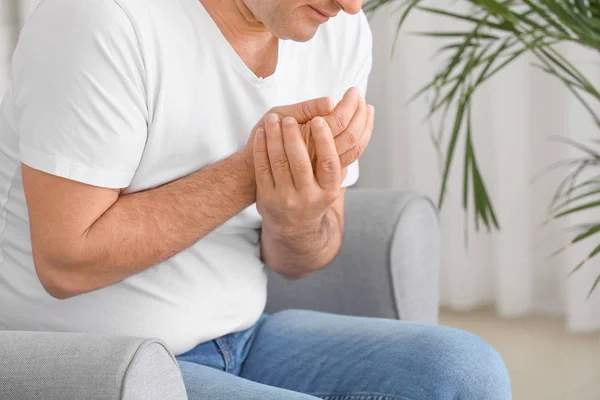Mature man suffering from pain in wrist at home — Stock Photo, Image