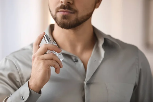 Handsome young man with bottle of perfume at home, closeup — Stock Photo, Image