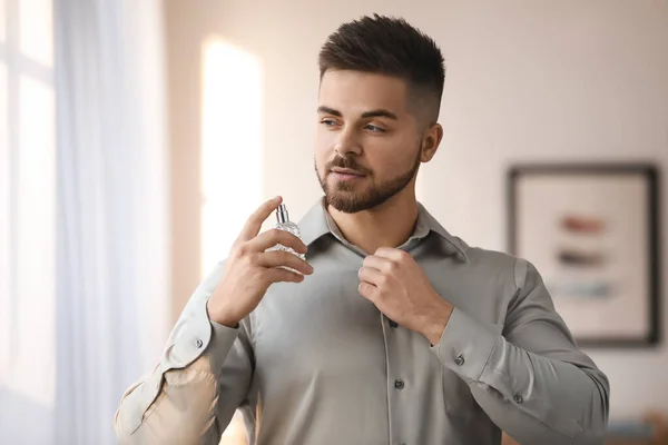 Handsome young man with bottle of perfume at home — 스톡 사진