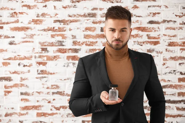 Joven guapo con botella de perfume sobre fondo de ladrillo —  Fotos de Stock