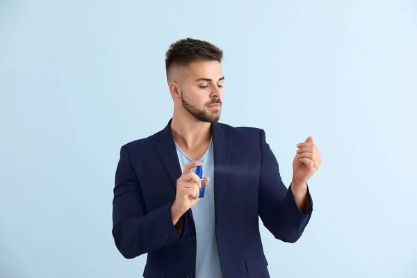 Beau jeune homme avec bouteille de parfum sur fond de couleur — Photo